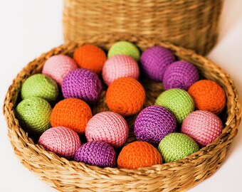 May include: A wicker basket filled with colourful crocheted balls in shades of pink, green, orange, and purple.