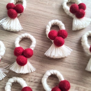 May include: Set of nine red and white napkin rings with a tassel. Each ring is made of white rope and has three red felt balls attached to it.