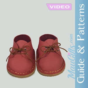 May include: Two pairs of red leather baby shoes with brown laces. The shoes have a stitched sole and a soft, rounded shape. The image also includes the word "VIDEO" in a pink banner.