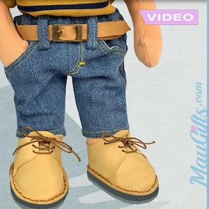 Puede incluir: Una muñeca con una camisa a rayas amarillas y negras, pantalones vaqueros azules, un cinturón marrón y zapatos marrones. La muñeca lleva un atuendo informal.