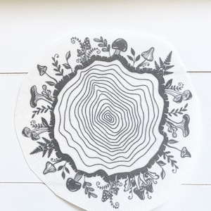 May include: A black and white illustration of a tree stump with a ring of mushrooms and leaves around it.
