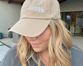 May include: A tan baseball cap with the text "JOHN 16 THREE" embroidered in white on the front.
