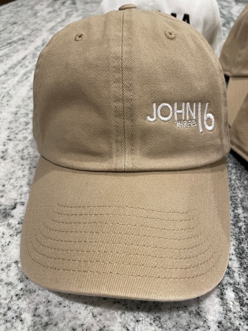 May include: A tan baseball cap with a white embroidered logo that says "JOHN16 THREE".