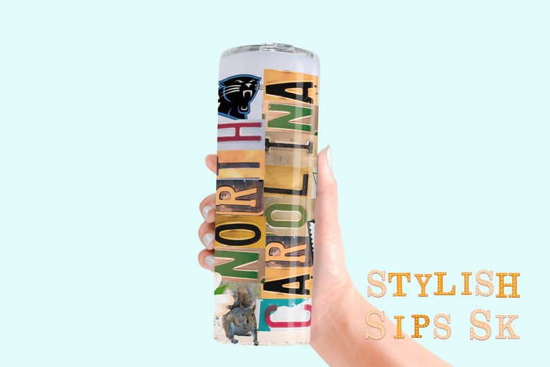 May include: A cylindrical tumbler featuring the Carolina Panthers logo and the words "NORTH CAROLINA" in a collage of various fonts and colors. A squirrel image is also present. The tumbler is held against a light blue background.