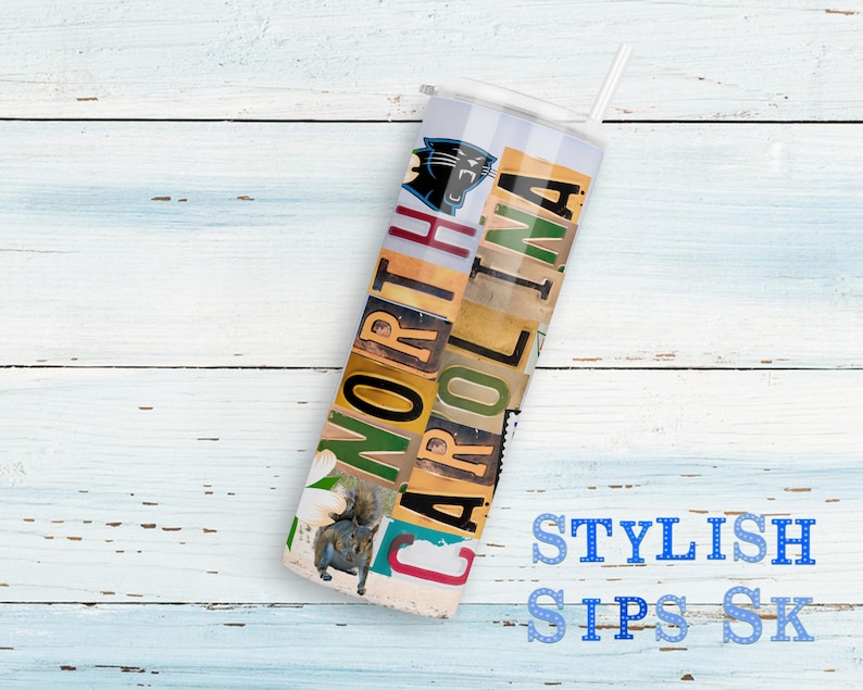 May include: A white tumbler with a straw, featuring the text "NORTH CAROLINA" in a collage of license plate letters. The design includes a Carolina Panthers logo and a squirrel image. The words "STYLISH SIPS SK" are also visible.