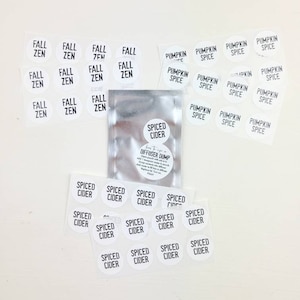 May include: A set of white round stickers with black text. The stickers feature various fall-themed scents, including "Fall Zen", "Spiced Cider", and "Pumpkin Spice".