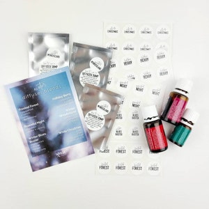 May include: A set of winter diffuser blends with labels for Frosted Forest, Holiday Berry, Peaceful Night, Winter Blues Buster, Winter Wonderland, and White Christmas. The set includes three small bottles of essential oils and three silver pouches with diffuser blends.