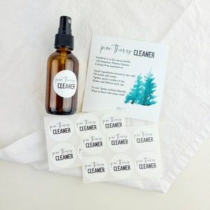 May include: A set of 10 round white stickers with black text that reads "pine thieves cleaner". The stickers are arranged in a circle around a brown glass spray bottle with a black spray nozzle. The bottle is labelled with the same text as the stickers. A white card with a watercolour illustration of a pine tree and the text "pine thieves cleaner" is visible in the background.