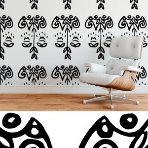 May include: A white wall with a repeating black abstract design. A modern white chair with a wooden base sits in front of the wall. The floor is made of wood.