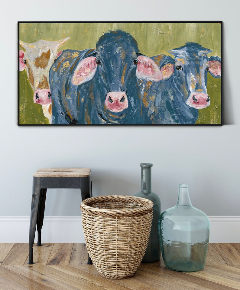 May include: A painting of three cows, two blue and one brown and white, with pink noses and ears. The cows are set against a green background.