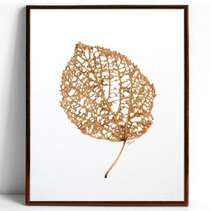 May include: A framed watercolor painting of a delicate, brown, leaf with a lacy, intricate pattern of holes. The leaf is depicted against a white background.