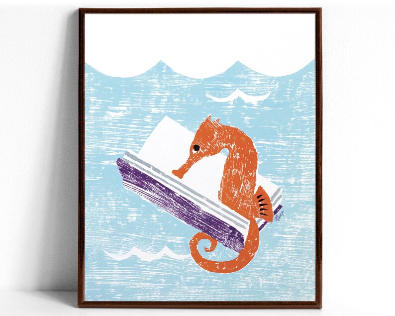 An art print of an orange seahorse reading the purple covered book he’s holding with his tail while floating in light blue water