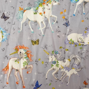 May include: A light gray fabric featuring a repeating pattern of white unicorns with colorful manes and horns. The design includes butterflies and floral accents, creating a whimsical and fantasy-themed textile.