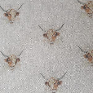May include: A white fabric with a repeating pattern of brown and white Highland cow heads. The cows have long horns and are facing forward.