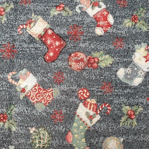 May include: A dark grey woven fabric featuring a repeating Christmas pattern of red and green stockings filled with candy canes and gifts, interspersed with red ornaments, holly berries, green leaves, and small red snowflakes throughout the design.