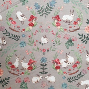 May include: A fabric pattern featuring white rabbits, red-capped mushrooms, and floral elements on a gray background. The design includes roses, leaves, and small flowers, creating a whimsical, nature-inspired theme.