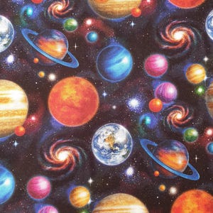 Könnte beinhalten: Ein Stoffdruck mit einem tiefschwarzen Weltraumhintergrund, gefüllt mit farbenfrohen Planeten, darunter beringte Gasriesen, erdähnliche Kugeln und wirbelnde Spiralgalaxien. Das Design enthält verschiedene Schattierungen von Orange, Blau, Lila und Gelb.