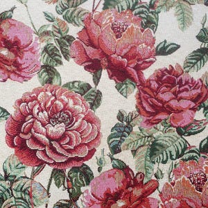 Puede incluir: Primer plano de una tela con un patrón floral. La tela presenta un patrón repetitivo de rosas rosas y rojas con hojas verdes sobre un fondo crema.
