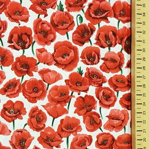 May include: Fabric with a repeating pattern of red poppy flowers on a white background. The poppies have dark centers and green stems. A wooden ruler with inch markings is on the right side of the image.