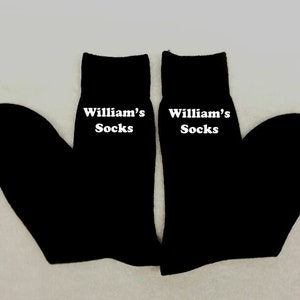 May include: A pair of black socks with white text that reads "William's Socks" on each sock.
