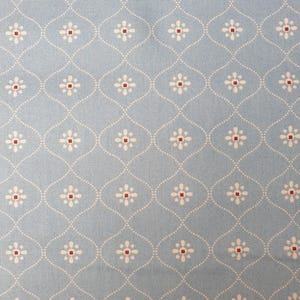 May include: A light blue fabric featuring a repeating pattern of white dotted ogee shapes. Each ogee contains a small white flower with a tiny red center. The textile has a visible woven texture throughout the entire surface of the material.