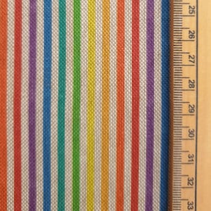 Può includere: Primo piano di un tessuto con strisce colorate in un motivo arcobaleno. Il tessuto è tessuto con una superficie testurizzata. Un righello è visibile sul lato destro dell'immagine.