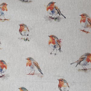 May include: A beige fabric with a repeating pattern of watercolor robins. The robins are depicted in various poses, with some facing left and others facing right. The fabric has a subtle texture and a light, airy feel.