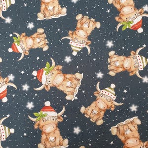 May include: A dark gray fabric featuring a repeating pattern of light brown Highland cattle wearing red or green winter hats with white pom-poms and green leaves. The background is filled with small white stars and snowflakes.
