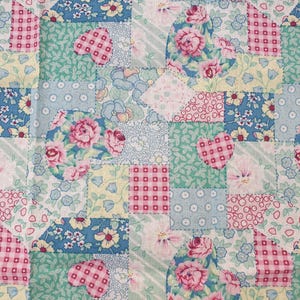 May include: A patchwork quilt with a repeating pattern of squares and heart shapes. The quilt features various floral and geometric patterns in shades of pink, blue, green, and yellow. The hearts are filled with floral designs.