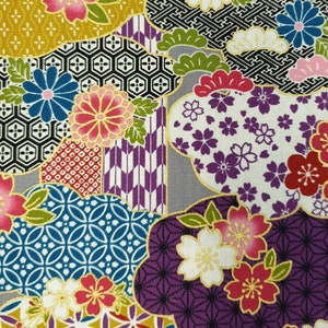 Pode incluir: Um tecido vibrante com um patchwork de padrões de inspiração japonesa. O design inclui flores estilizadas, formas geométricas e motivos em forma de nuvem numa rica paleta de cores, incluindo dourado, roxo, rosa, azul e branco.