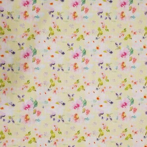 May include: Floral fabric with a light yellow background. The fabric features a repeating pattern of watercolor-style flowers in pink, white, and purple, with green leaves. A ruler is visible along the left edge.