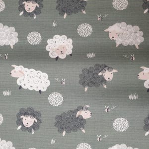 May include: A fabric design with a repeating pattern of cartoon sheep in white and grey, with pink faces and black legs, on a muted green background. White dotted circles, bees, and grass tufts are also included.
