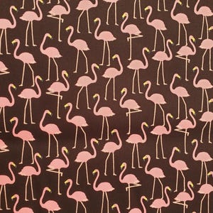 Könnte beinhalten: Ein brauner Stoff mit einem sich wiederholenden Muster aus rosa Flamingos. Die Flamingos sind in verschiedene Richtungen ausgerichtet und haben einen gelben Schnabel und schwarze Augen.