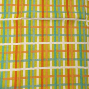 May include: Close-up of a fabric with a grid pattern. The design features intersecting vertical and horizontal lines in orange, teal, and green against a white background. The fabric has a textured appearance.