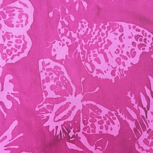 May include: A vibrant magenta fabric featuring a repeating pattern of light pink butterflies and dragonflies. The design displays a batik-style aesthetic with intricate wing details and organic shapes scattered across the surface of the textile.
