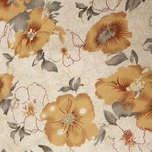 Puede incluir: Una tela blanca con un patrón floral. Las flores son de color marrón claro con un centro marrón más oscuro. El fondo es de color crema claro.