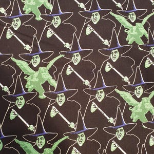 May include: A repeating pattern featuring the Wicked Witch of the West from The Wizard of Oz. The witch is depicted in a black outfit and hat with a green face, holding a broom. Some images include a green winged monkey.