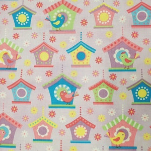 Puede incluir: Una tela rosa con un patrón repetido de casas de pájaros coloridas con pájaros. Las casas de pájaros tienen diferentes colores y patrones, incluyendo verde, azul, amarillo y morado. Los pájaros también son de diferentes colores, incluyendo rojo, amarillo y verde.