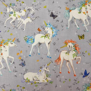 May include: A gray fabric featuring a repeating pattern of white unicorns with colorful manes and tails, yellow horns, and floral accents. The design includes small butterflies in blue, orange, and black, along with scattered green leaves and white stars.