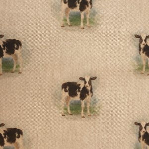 May include: A beige fabric with a repeating pattern of black and white calves. The calves are standing on a green grassy field.