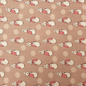 May include: A pink fabric with a repeating pattern of white rabbits wearing red jackets. The rabbits are facing left and right, and the background is a light pink with small white dots.