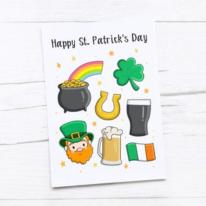 Op de afbeelding: Een witte kaart met de tekst "Happy St. Patrick's Day" en illustraties van een pot goud, een regenboog, een klavertjevier, een hoefijzer, een pint bier, een glas bier, een kabouter en de Ierse vlag.
