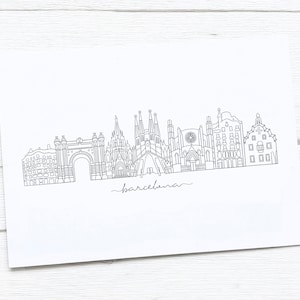 May include: A black and white line drawing of the Barcelona skyline, featuring iconic landmarks like the Sagrada Familia and Arc de Triomf. The word "barcelona" is written in cursive below the skyline.