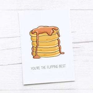 Op de afbeelding: Een kaart met een cartoonillustratie van een stapel pannenkoeken met siroop. De tekst op de kaart luidt "You're the flipping best."