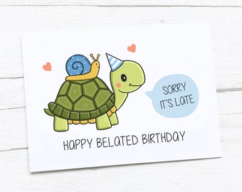 May include: A white card with a green turtle wearing a blue and white party hat and a yellow snail on its back. The turtle is saying "Sorry it's late" in a blue speech bubble. The card says "Happy Belated Birthday".