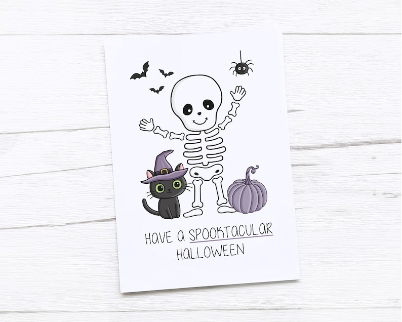 May include: A white card with a Halloween-themed illustration. It features a cartoon skeleton, a black cat wearing a witch hat, a purple pumpkin, bats, and a spider. The text reads "Have a Spooktacular Halloween."