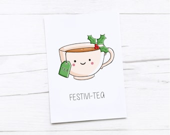 May include: A white greeting card featuring a cartoon teacup filled with tea. The teacup has a smiling face, a green tea bag, and holly sprigs. The text "FESTIVI-TEA" is printed below the teacup.
