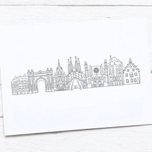 May include: A black and white line drawing of the Barcelona skyline, featuring iconic landmarks such as the Sagrada Familia and Arc de Triomf. The artwork is on a white rectangular paper, perfect for framing or gifting.