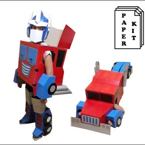 May include: A red, blue, and white paper kit costume resembling a robot. The costume includes a helmet, chest, arms, and legs. A second, similar robot truck is also shown. The text "PAPER KIT" is visible.