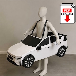 Puede incluir: Un disfraz de coche blanco con ventanas negras, ruedas negras y tirantes negros usado por un maniquí. La imagen incluye un icono blanco con el texto PDF DIGITAL FILE y una flecha roja apuntando hacia abajo, indicando un patrón descargable.